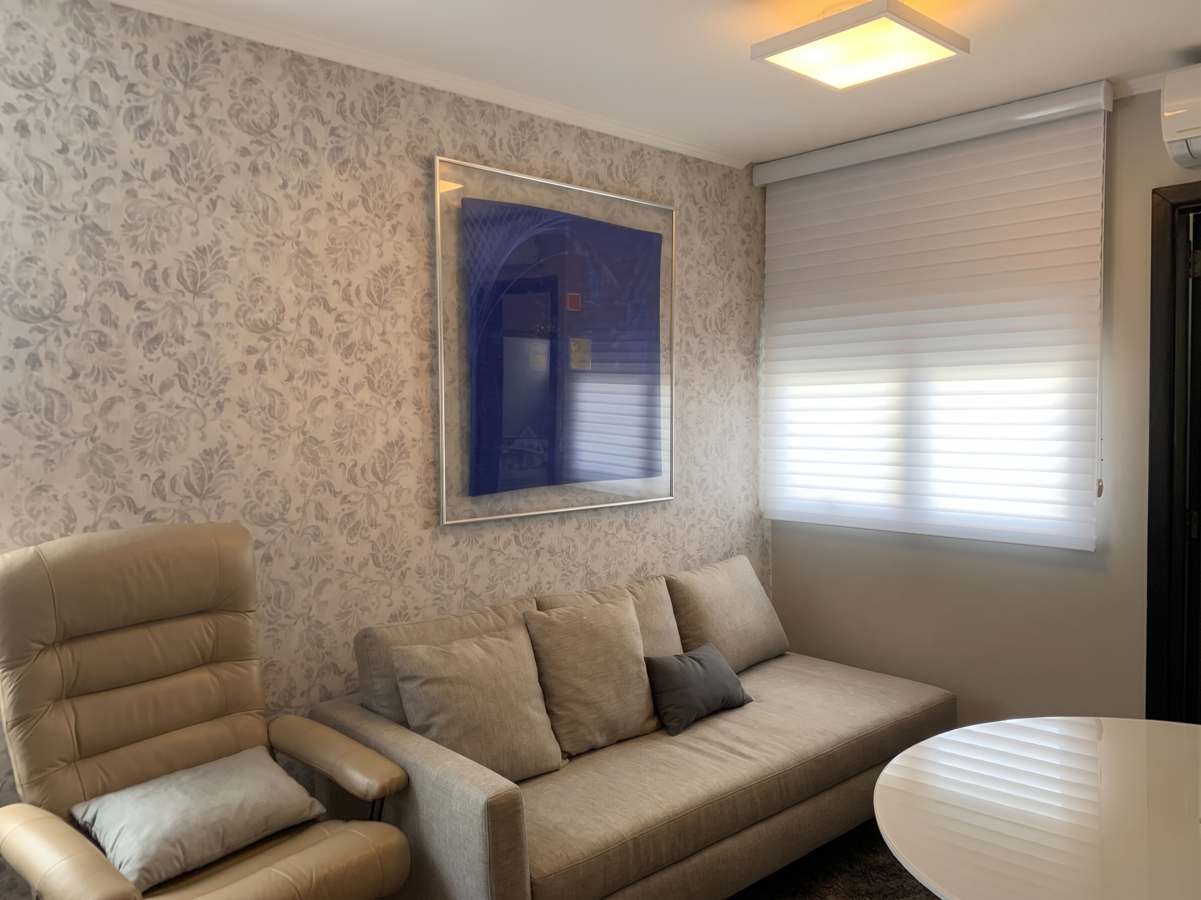 Sala de atendimento com poltrona, sofá e uma mesa